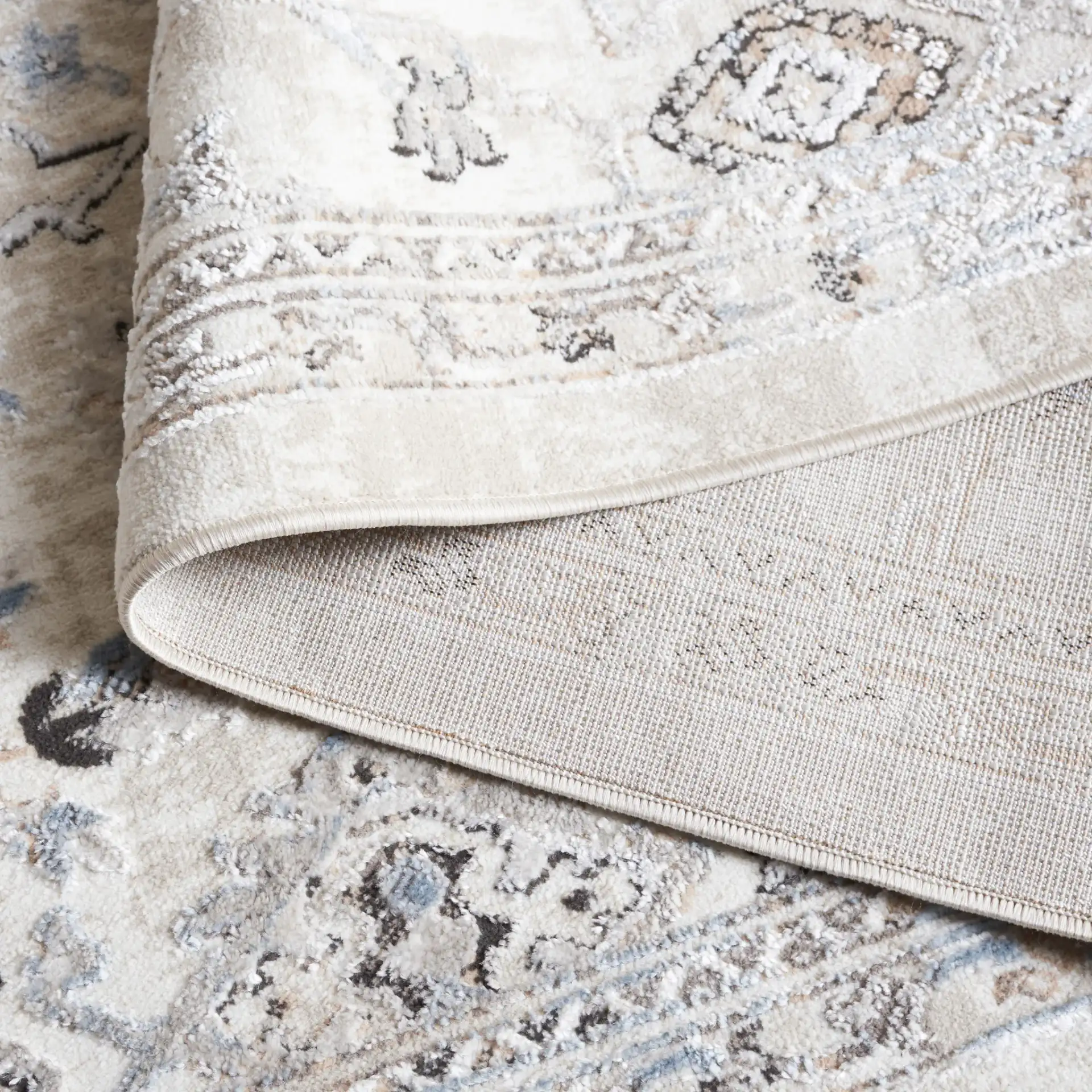 Quincy Distressed Floral Bordered Rug in Ivory / Beige in a styled room