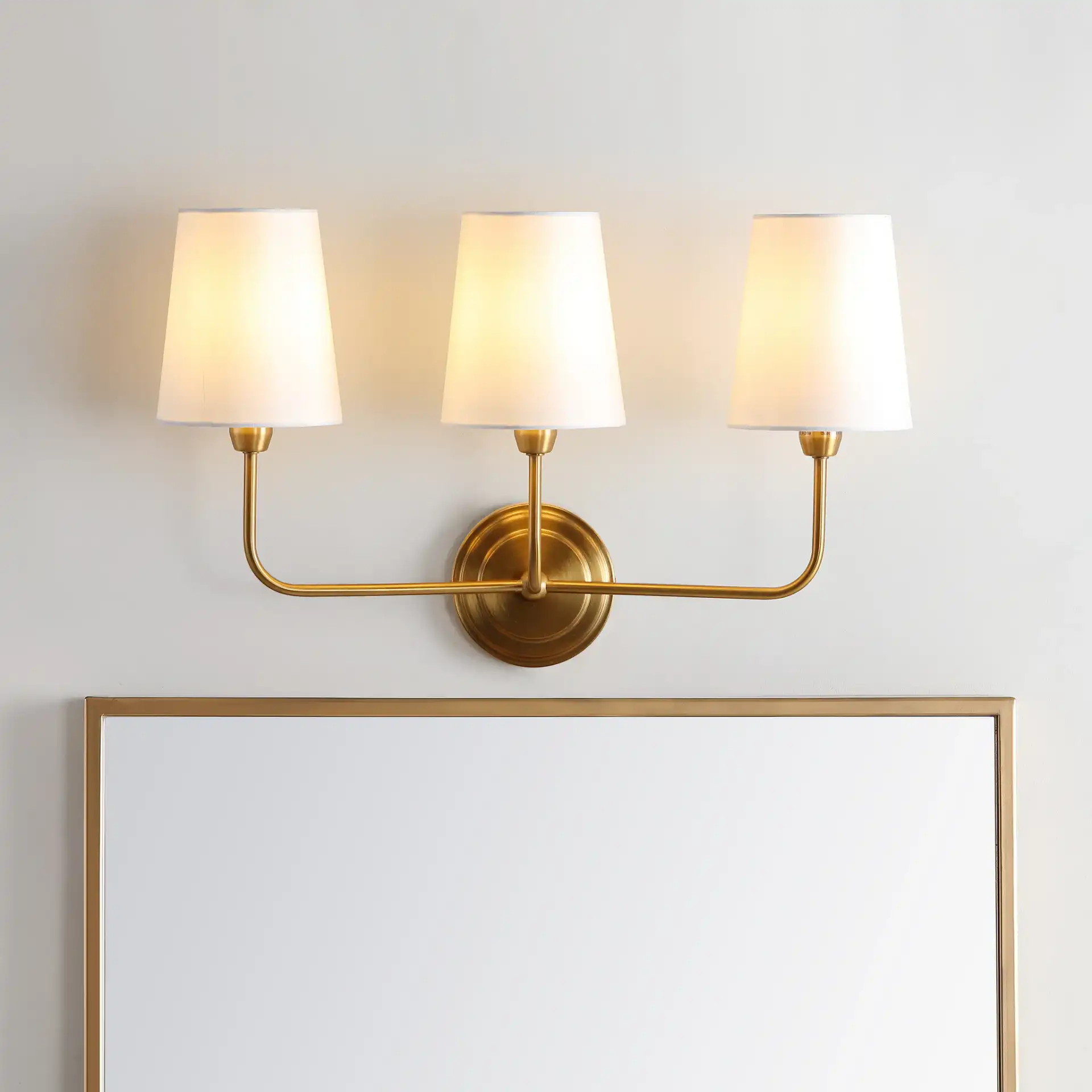 Sawyer Three-Light Wall Sconce in Brass in a styled room