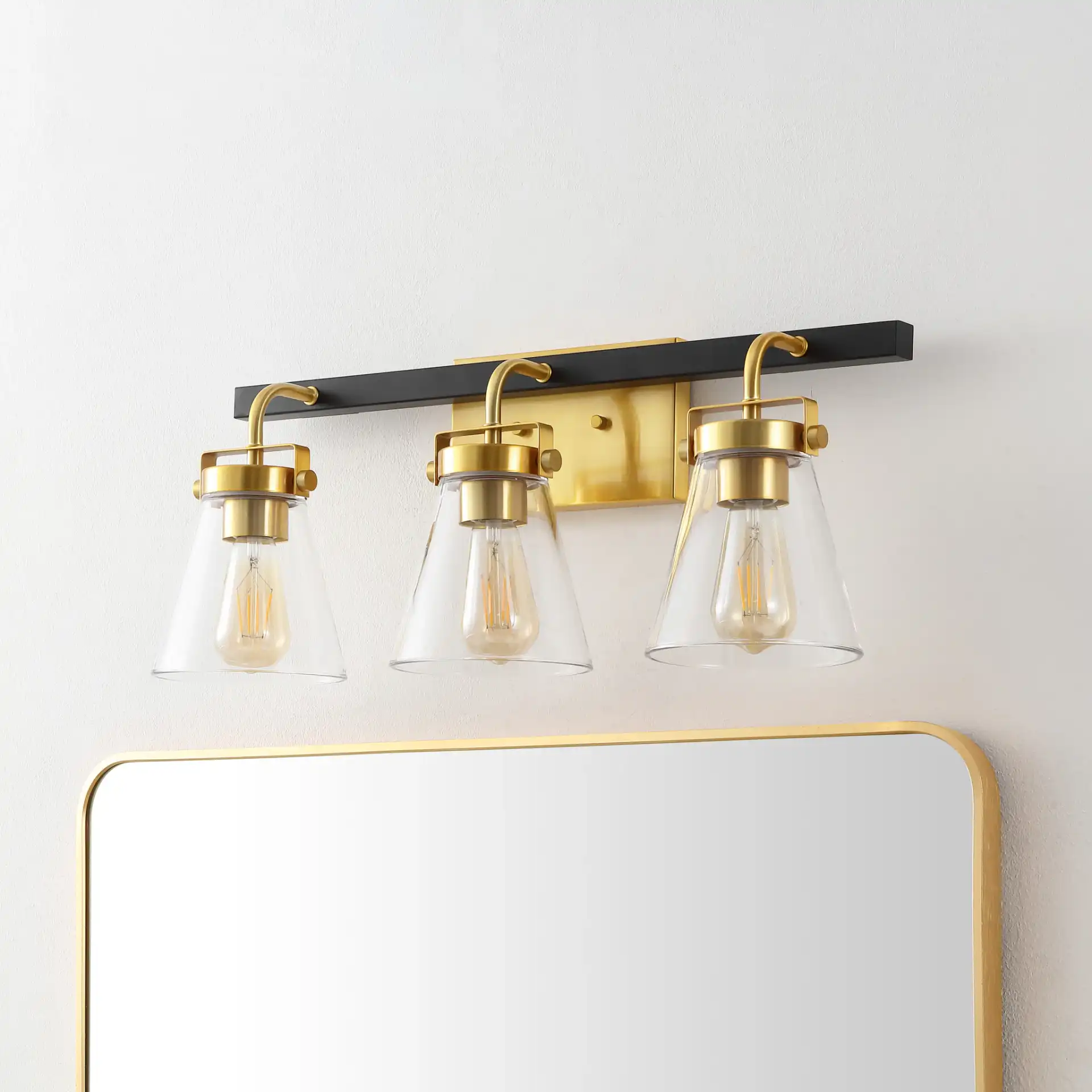 Rayney Three-Light Wall Sconce in Brass / Black in a styled room