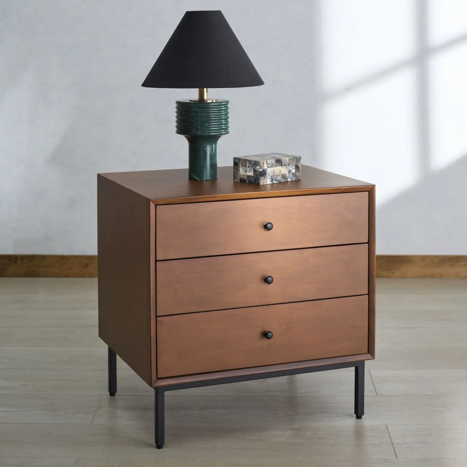 Trever Wood Three-Drawer Nightstand in Walnut / Black in a styled room
