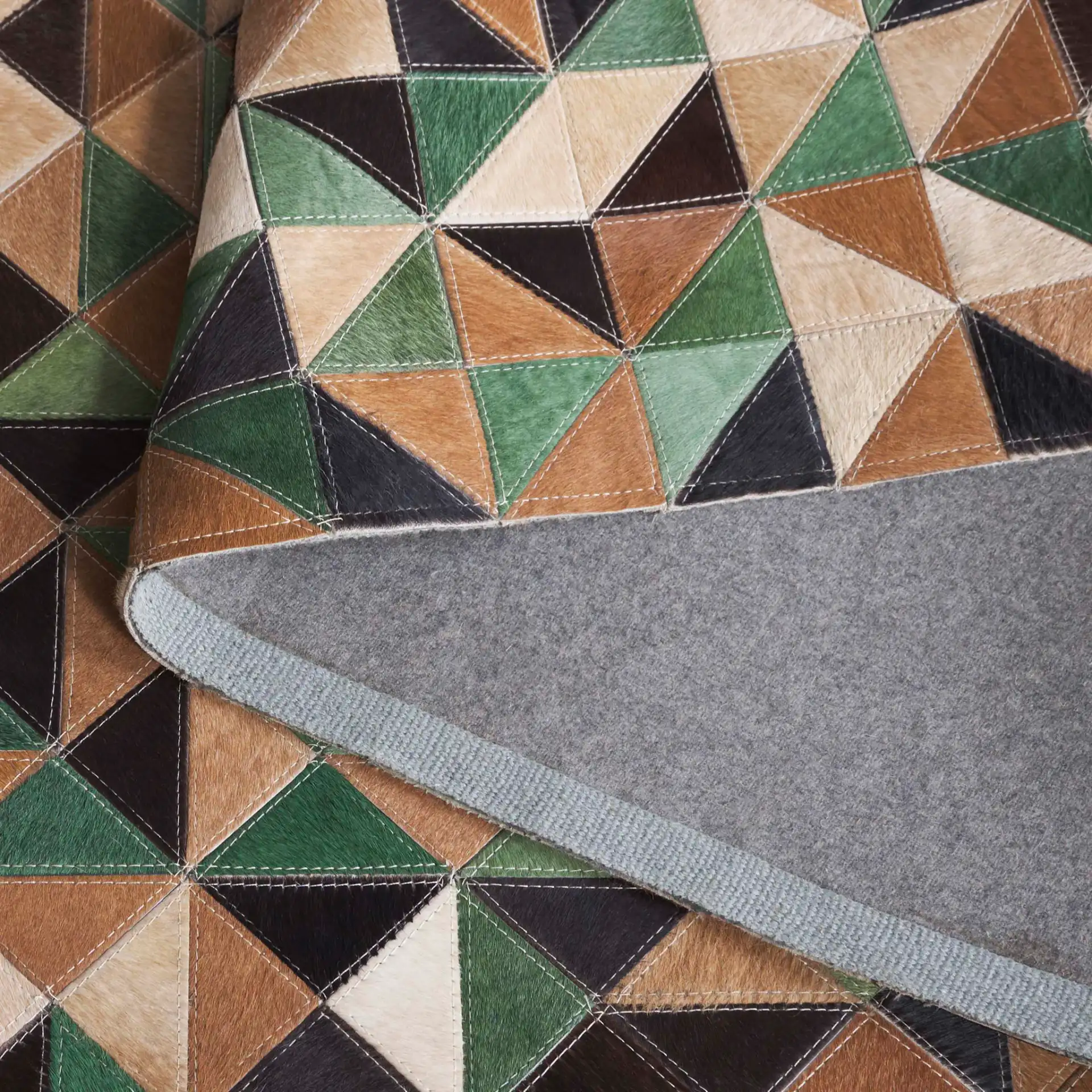Studio Leather Modern Patchwork Geometric Hand-Woven Rug in Green / Light Brown in a styled room