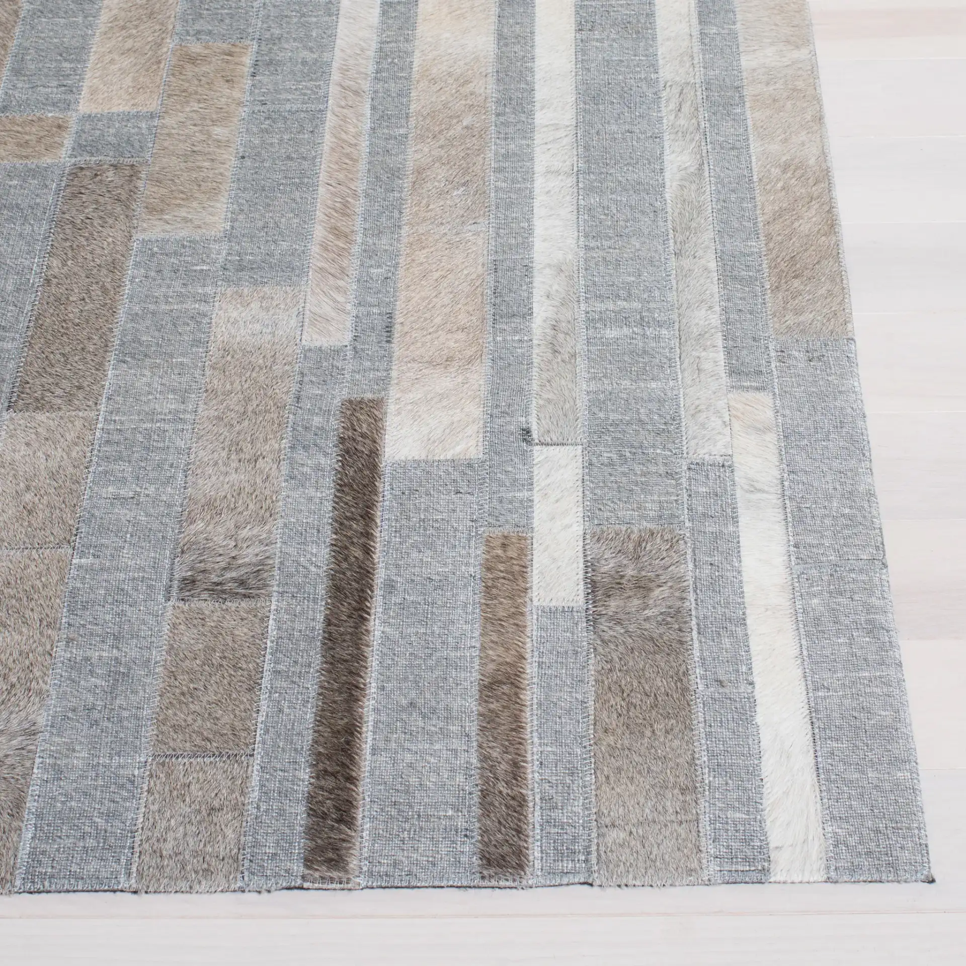 Studio Leather Linear Patchwork Hand-Woven Rug in Ivory / Gray in a styled room