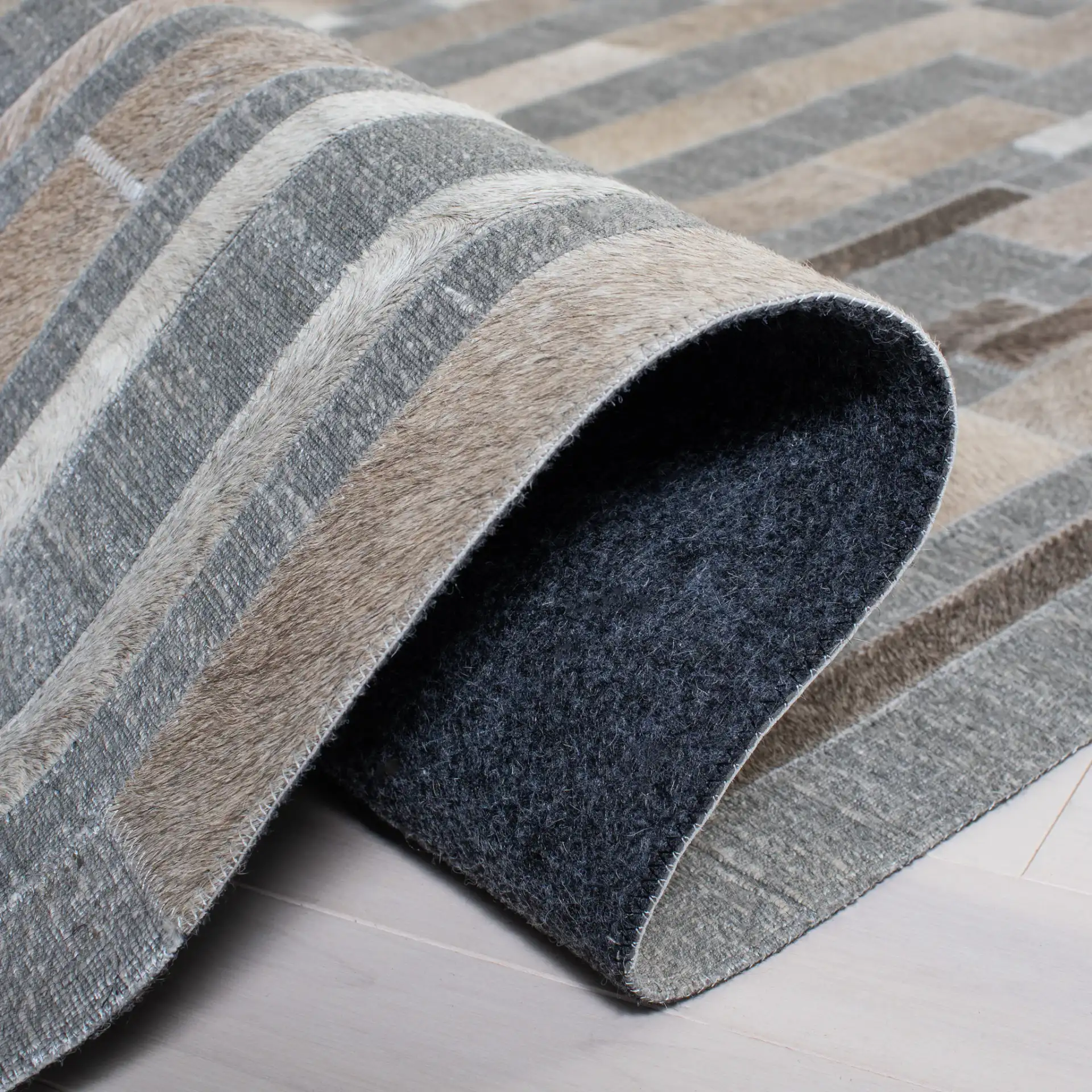 Studio Leather Linear Patchwork Hand-Woven Rug in Ivory / Gray in a styled room