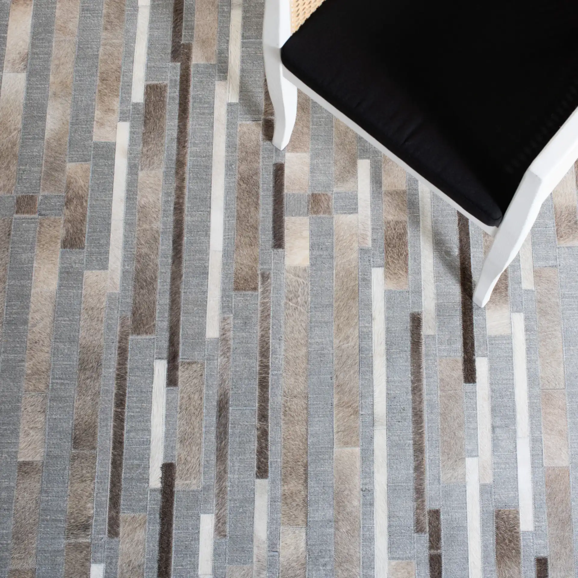 Studio Leather Linear Patchwork Hand-Woven Rug in Ivory / Gray in a styled room