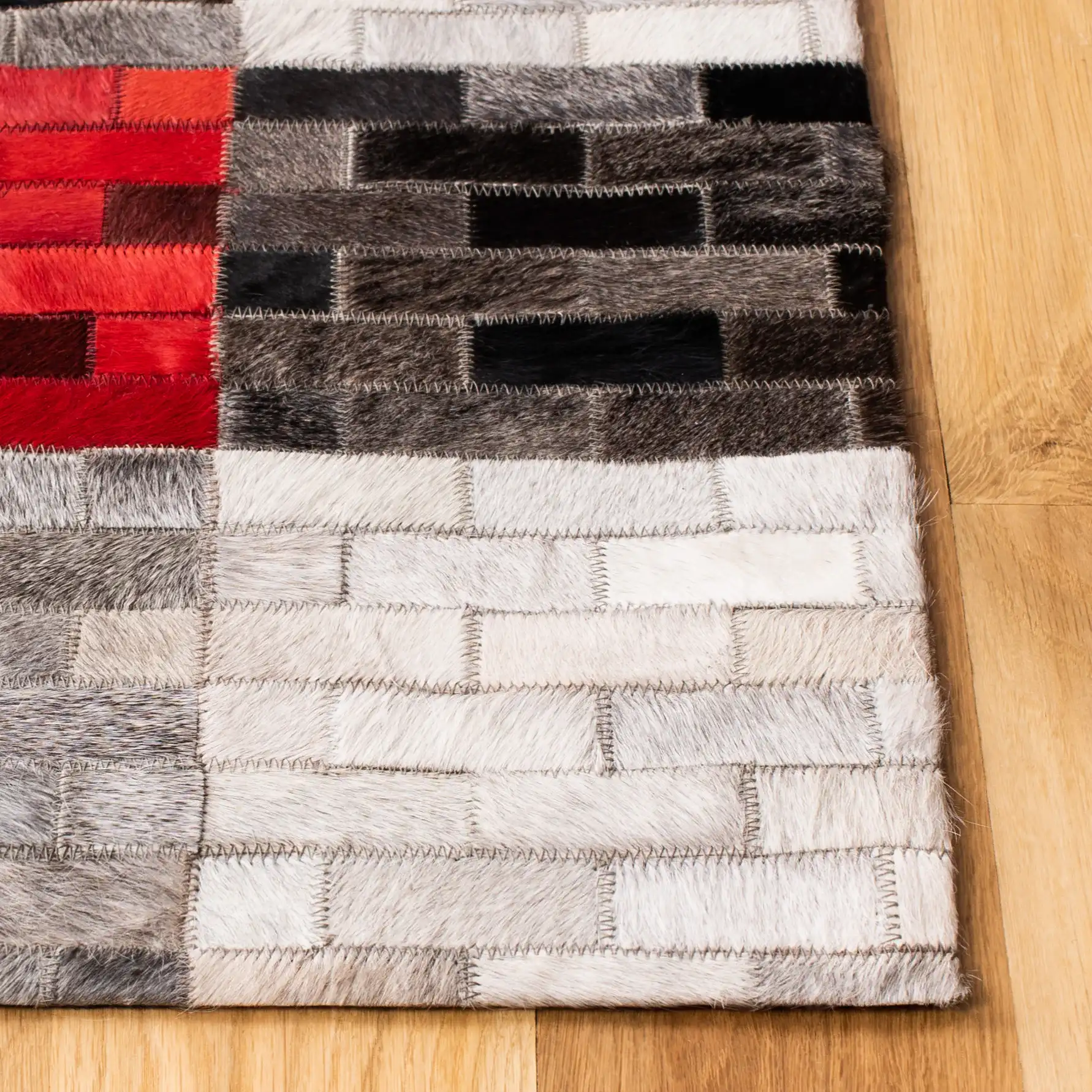 Studio Leather Checkerboard Patchwork Hand-Woven Rug in Gray / Red in a styled room