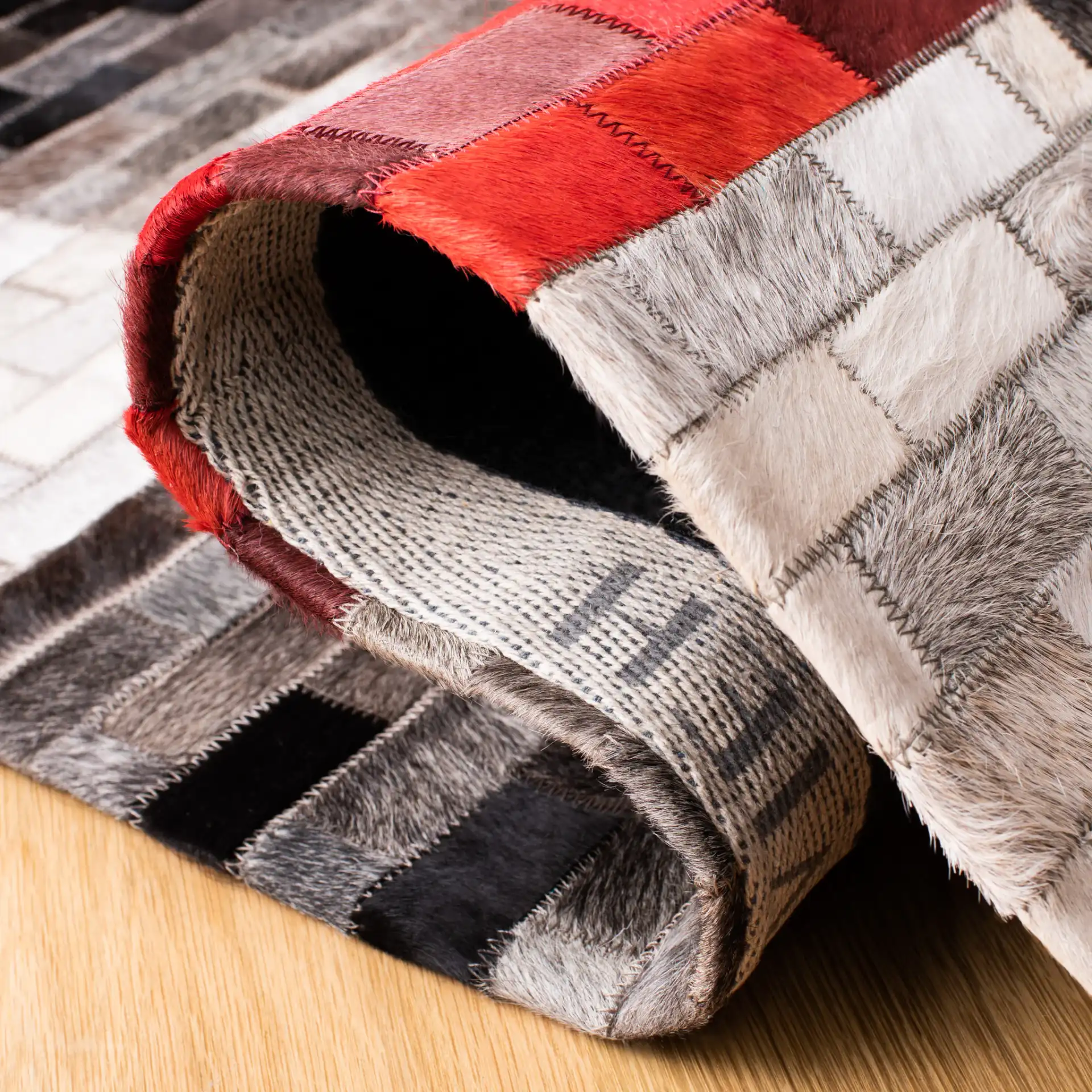 Studio Leather Checkerboard Patchwork Hand-Woven Rug in Gray / Red in a styled room