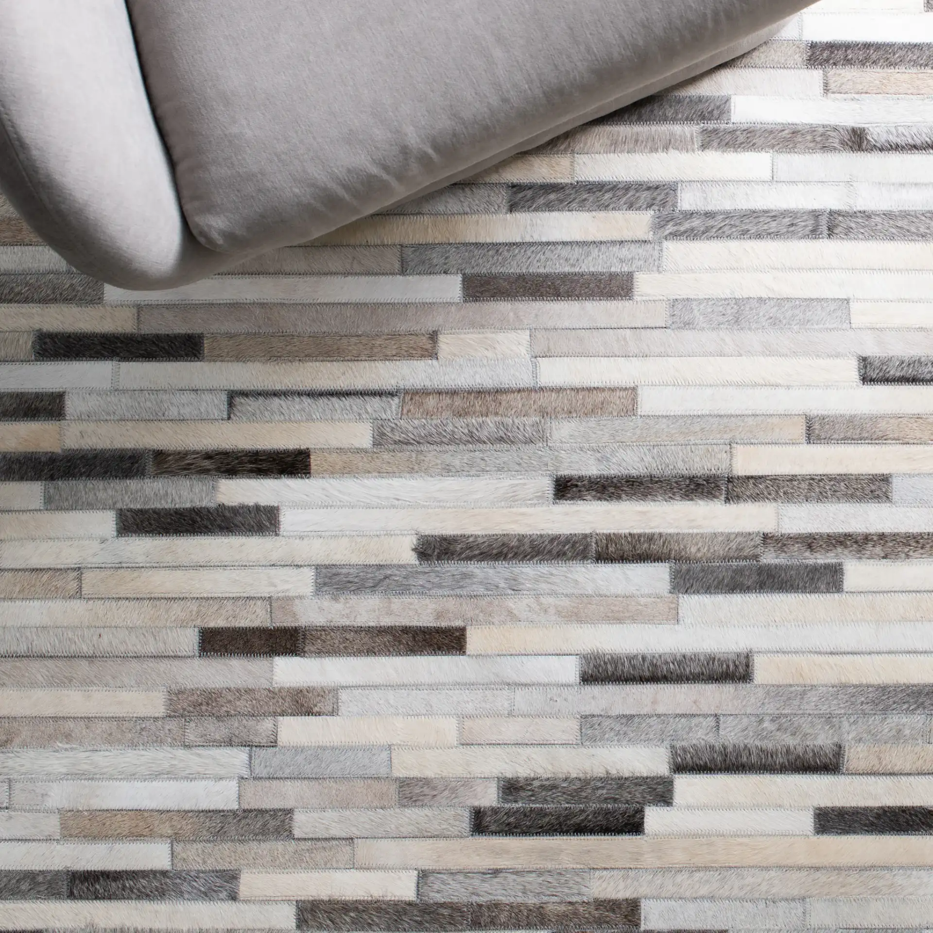 Studio Leather Brick Patchwork Hand-Woven Rug in Ivory / Gray in a styled room