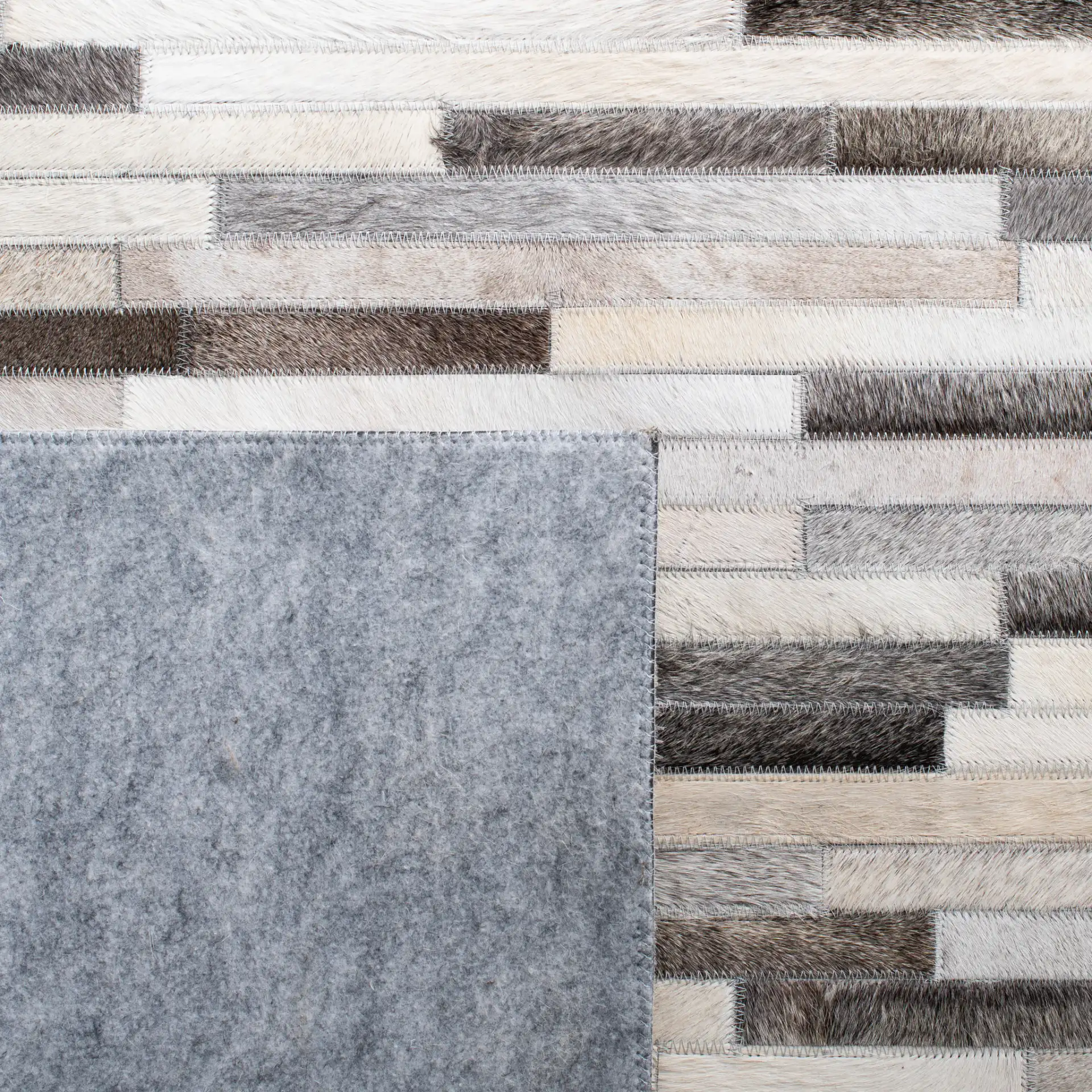 Studio Leather Brick Patchwork Hand-Woven Rug in Ivory / Gray in a styled room