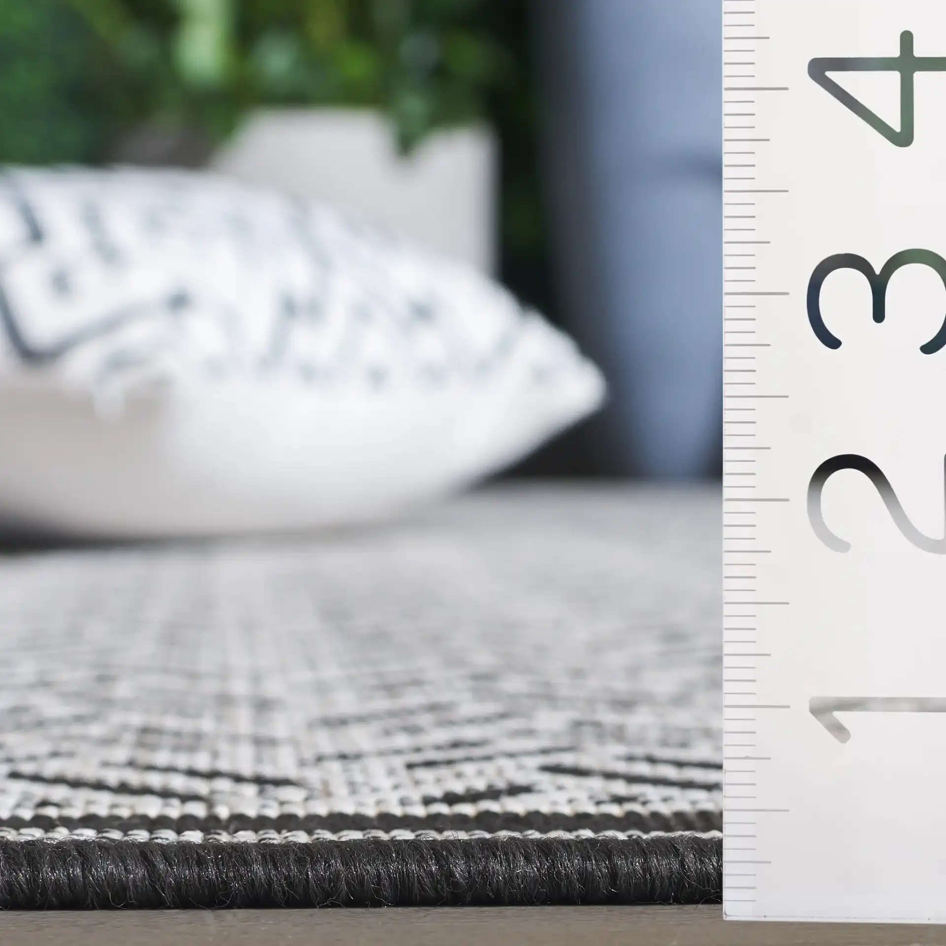 Terrace Basketweave Border Outdoor Rug in Black / White in a styled room