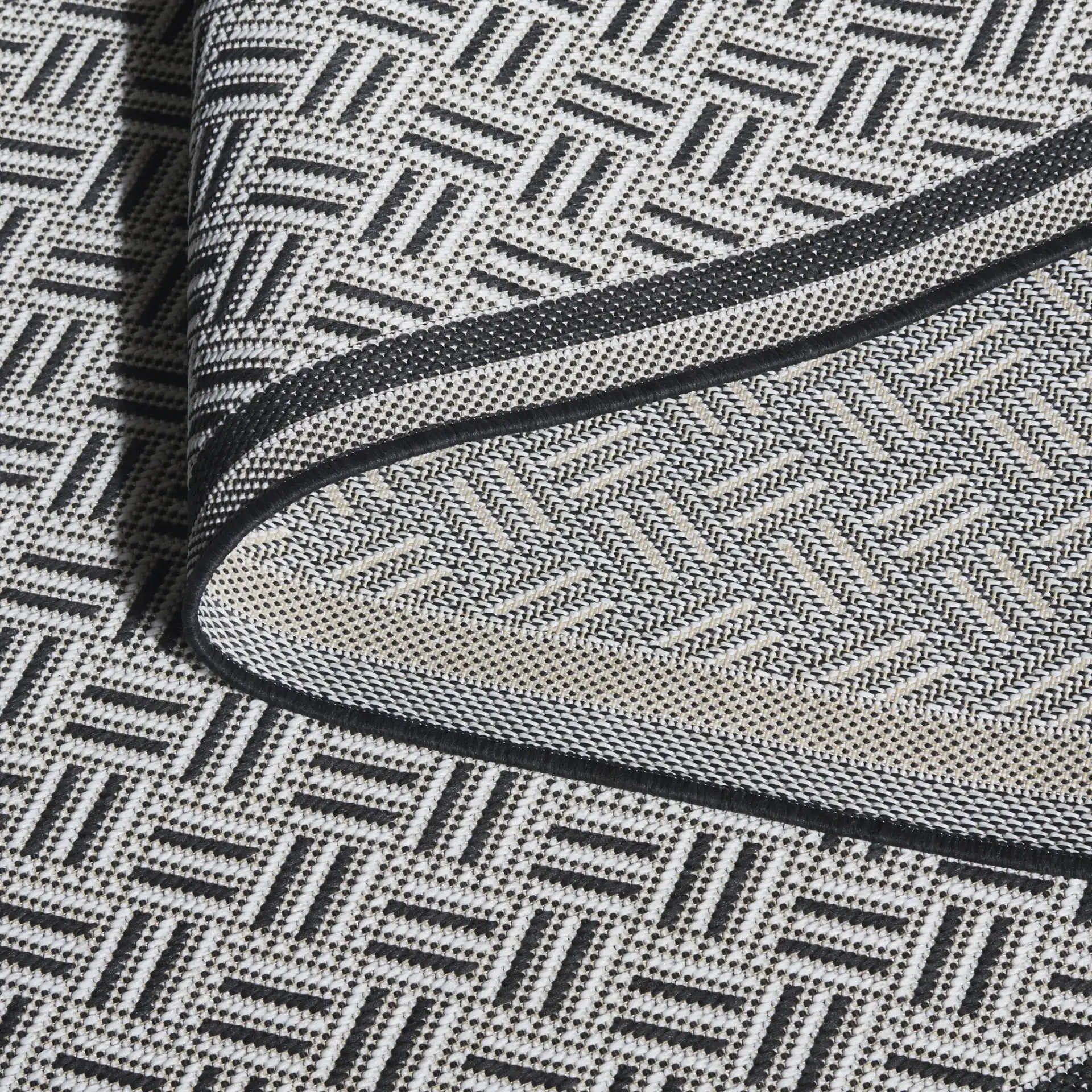 Terrace Basketweave Border Outdoor Rug in Black / White in a styled room