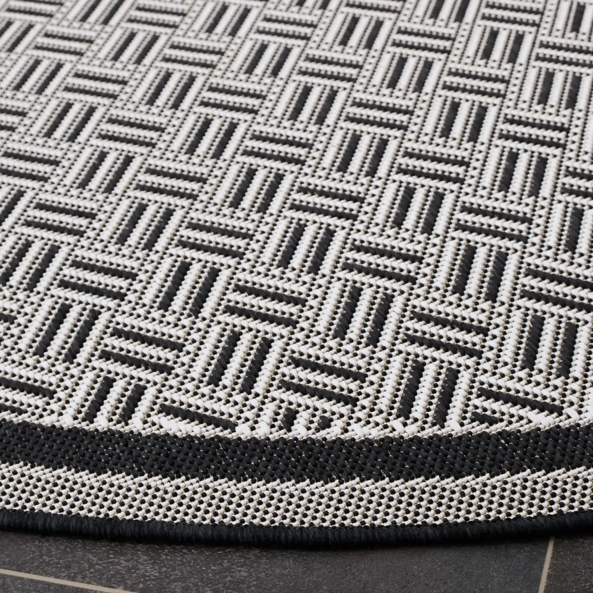 Terrace Basketweave Border Outdoor Rug in Black / White in a styled room