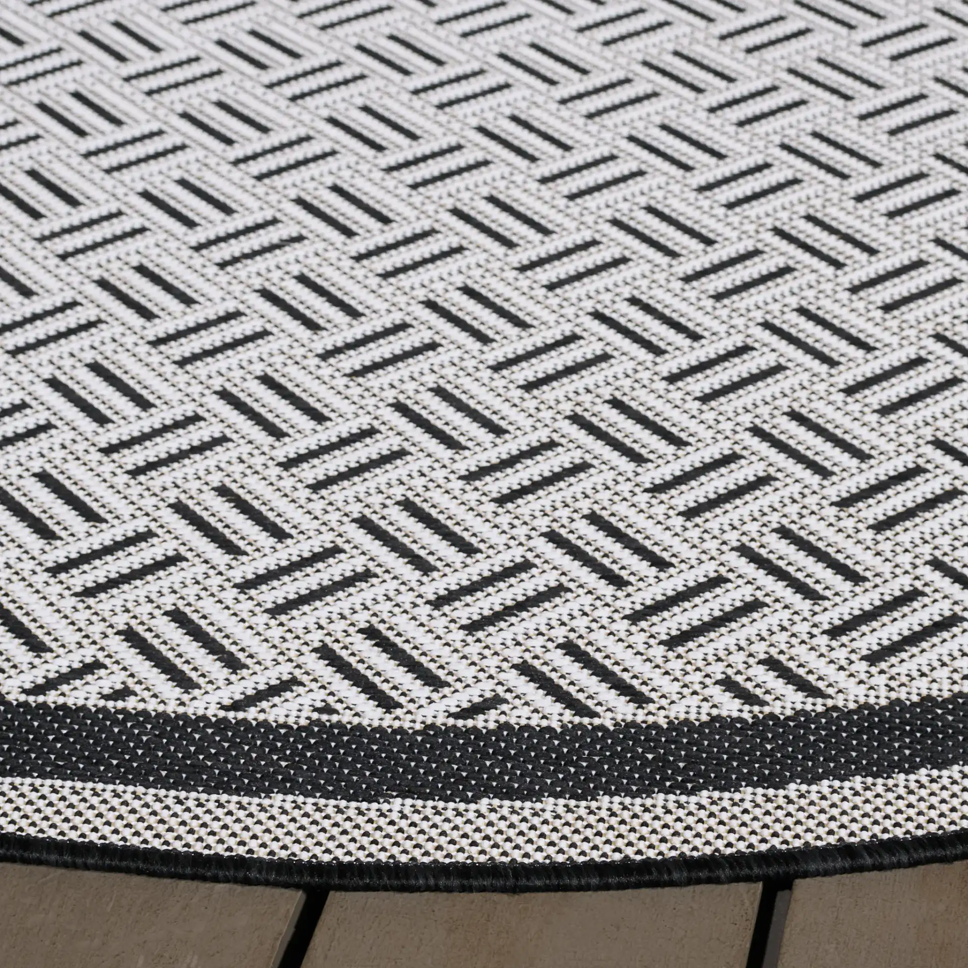 Terrace Basketweave Border Outdoor Rug in Black / White in a styled room