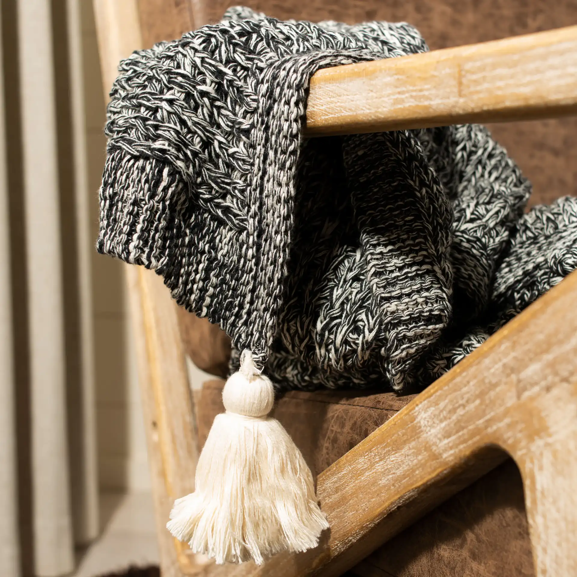 Pennie Knit Tassel Throw in Black / Natural in a styled room