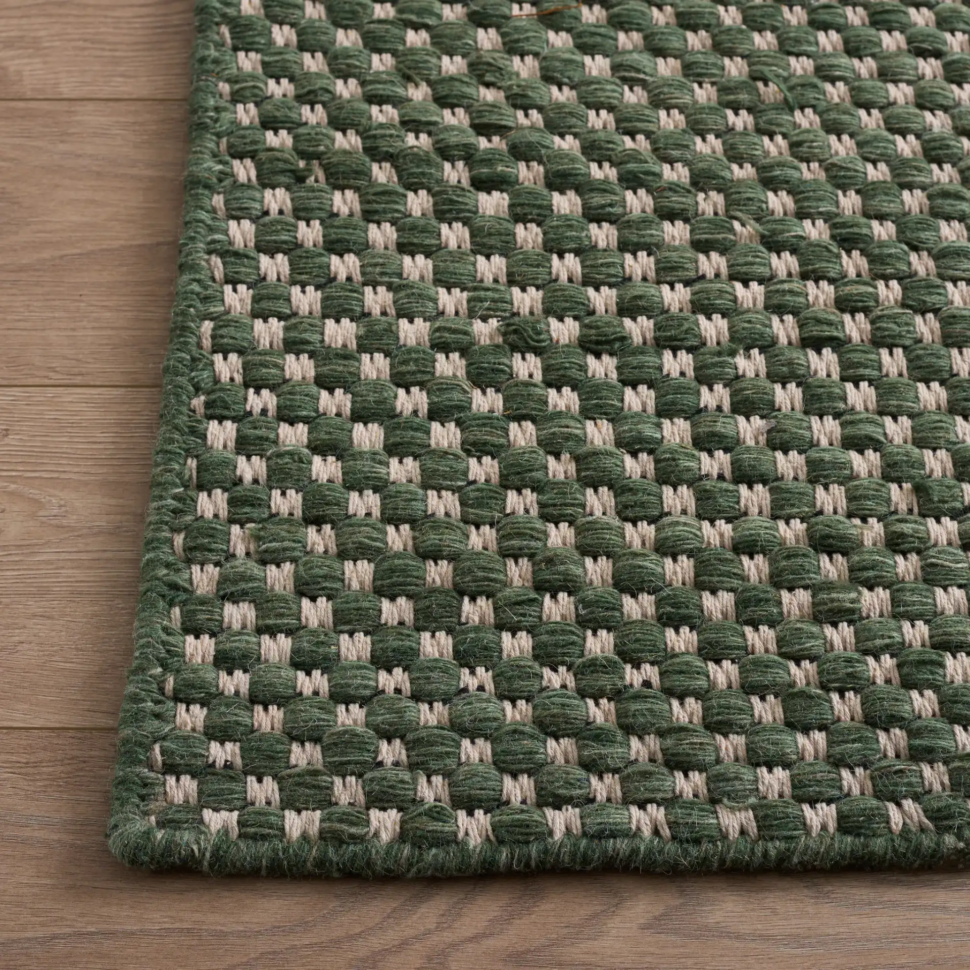 Vermont Pebbled Flatweave Wool Rug in Green / Ivory in a styled room