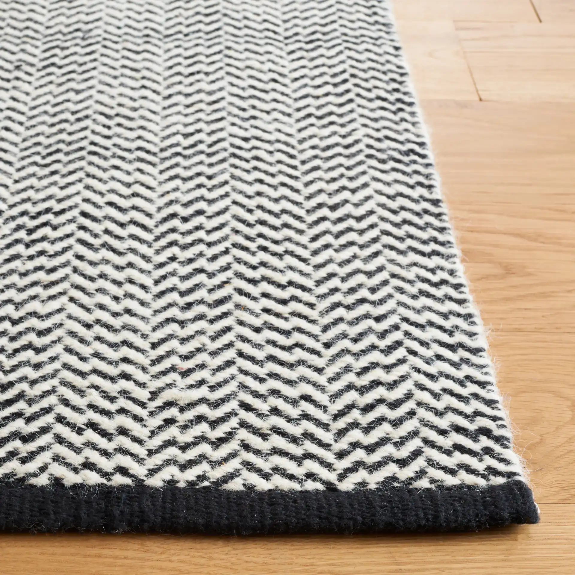 Vermont Chevron Hand-Woven Wool Rug in Black / Ivory in a styled room