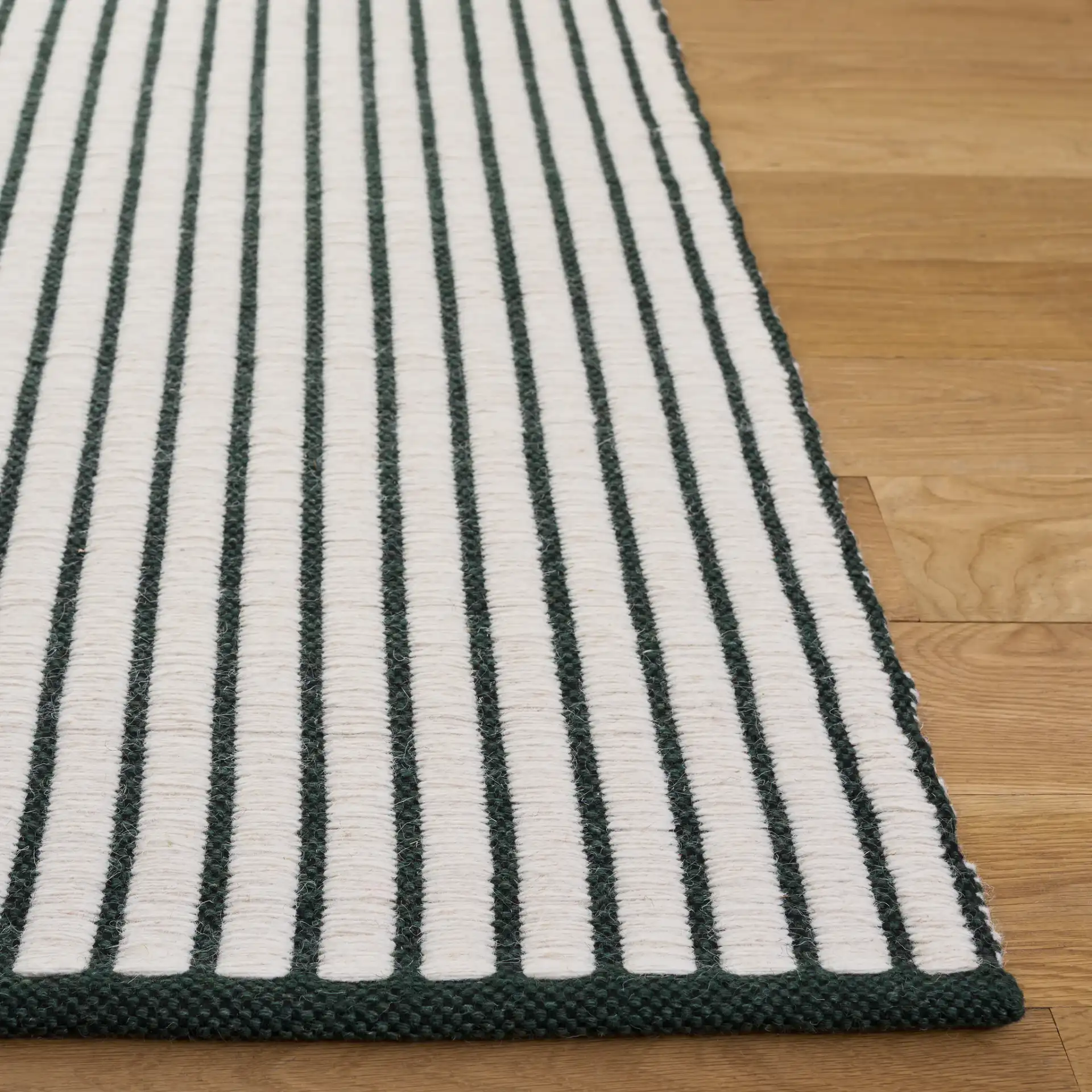 Vermont Pinstripe Hand-Woven Wool Rug in Dark Green / Ivory in a styled room