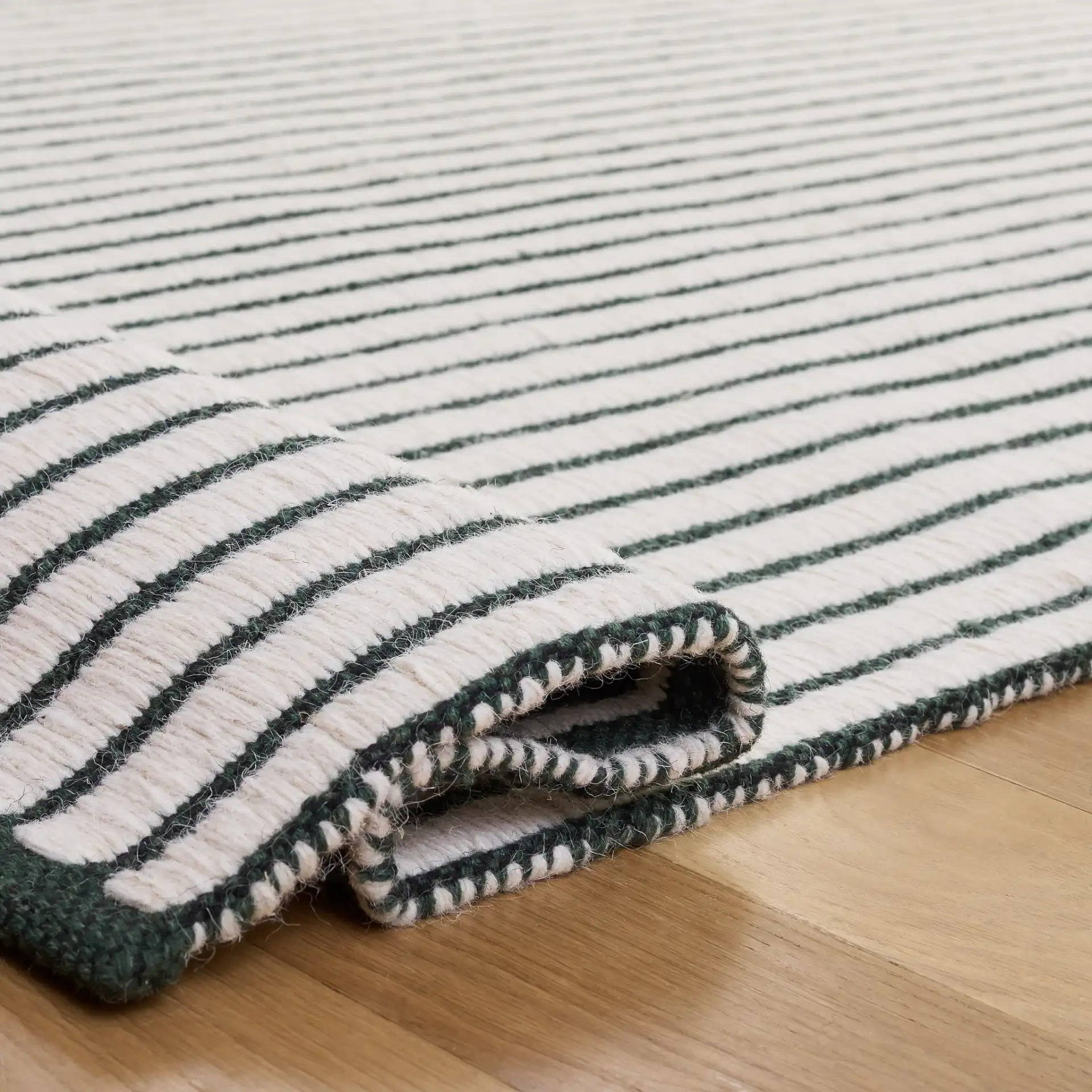 Vermont Pinstripe Hand-Woven Wool Rug in Dark Green / Ivory in a styled room