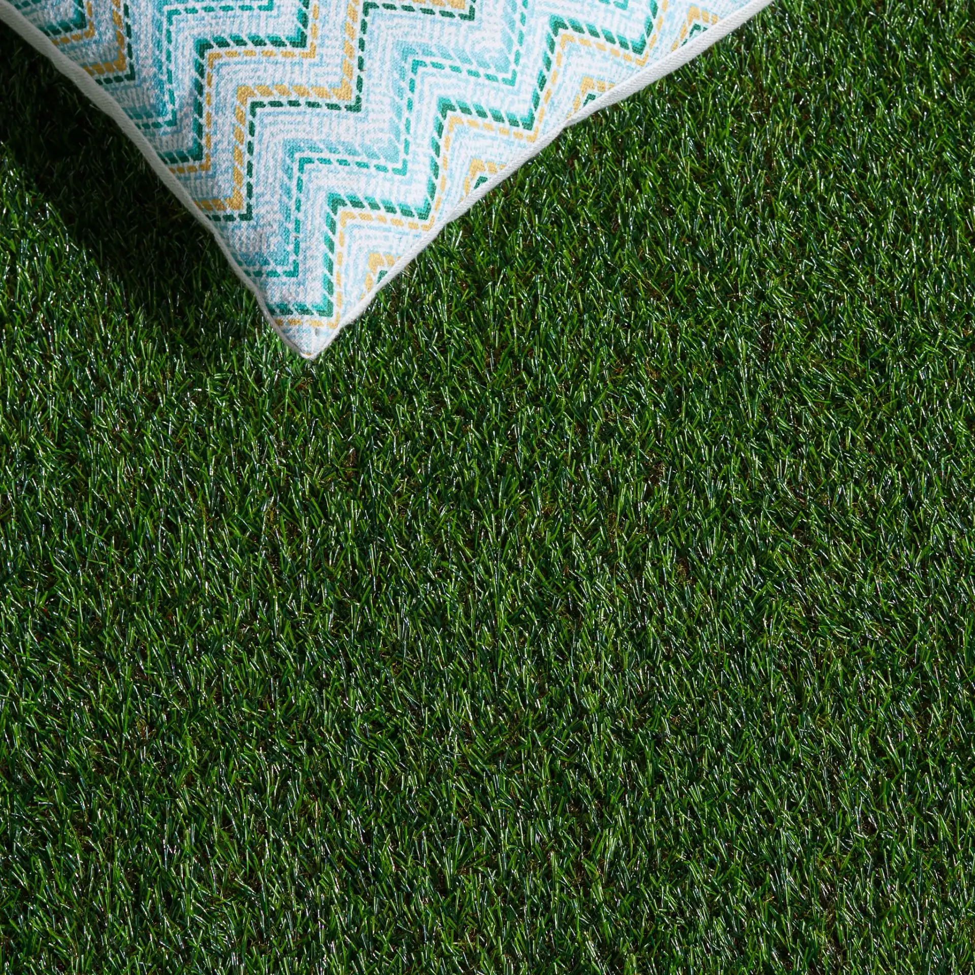 Turf Textured Solid Outdoor Rug in Natural / Green in a styled room